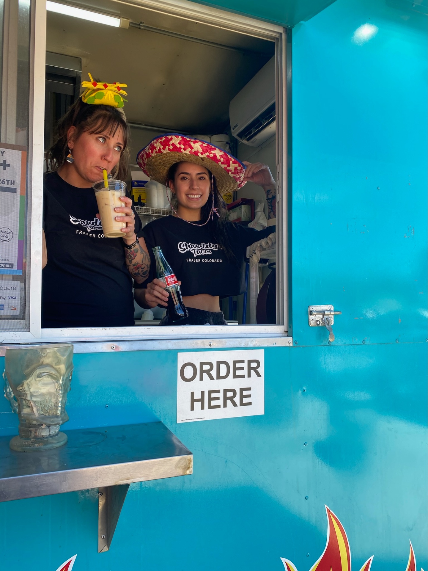 Two Shreddy's staff at the order window with a Coke and an iced coffee