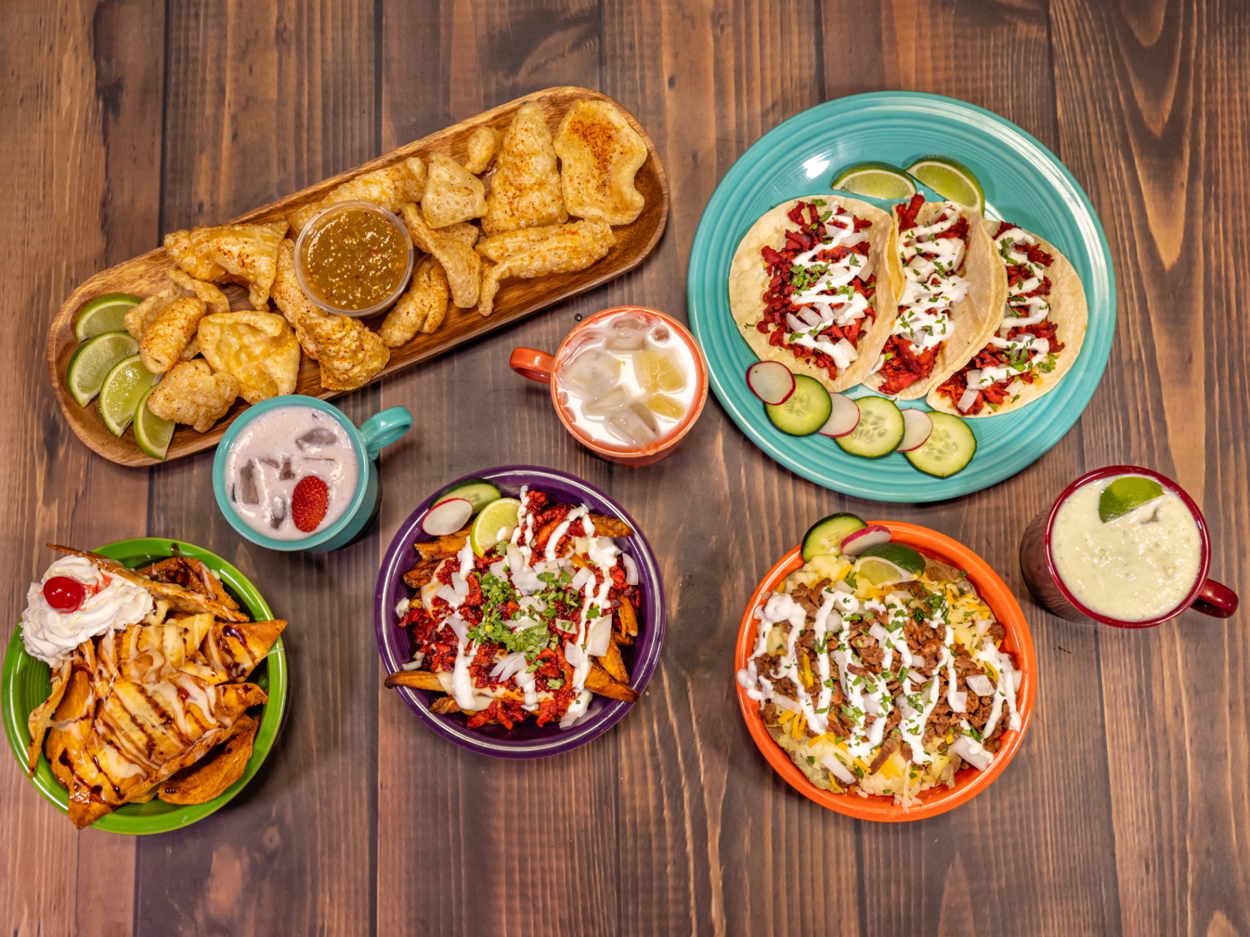 Spread of authentic birria, al pastor, and carnitas tacos with salsa verde and lime on a moody concrete surface